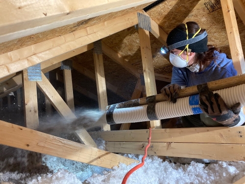 Person insulating atiic with cellulose blower