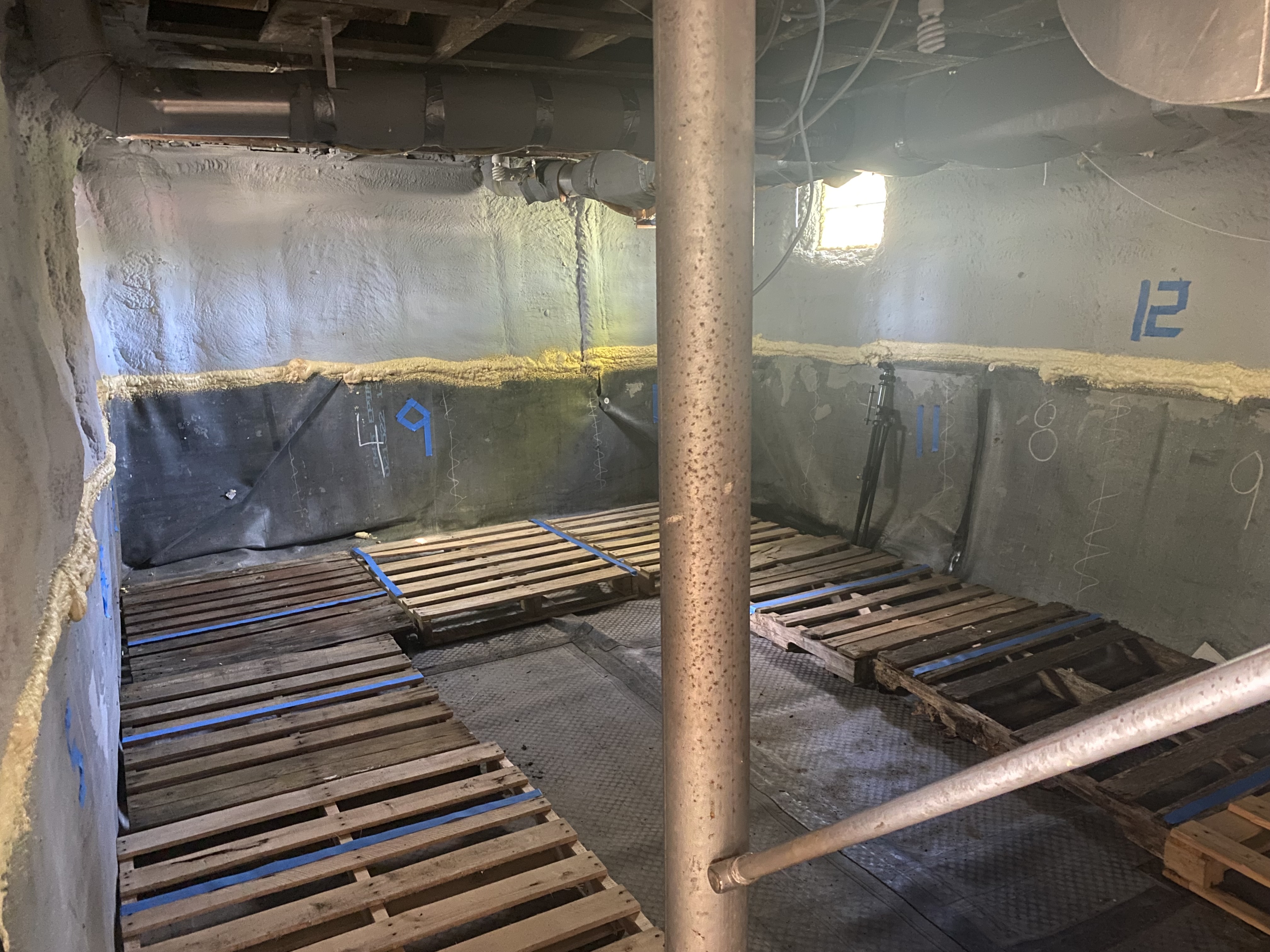 Image of the basement of Cottage after energy improvements have been made. The walls have been spray foamed and there is thick rubber vapor barrier over the floor and half way up the walls.